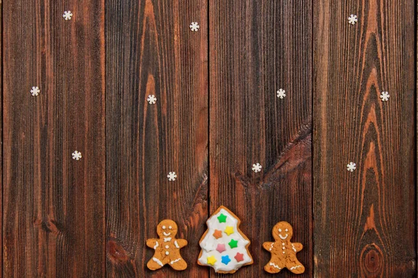 Christmas gingerbread man cakes around a Christmas tree on a bro — Stock Photo, Image