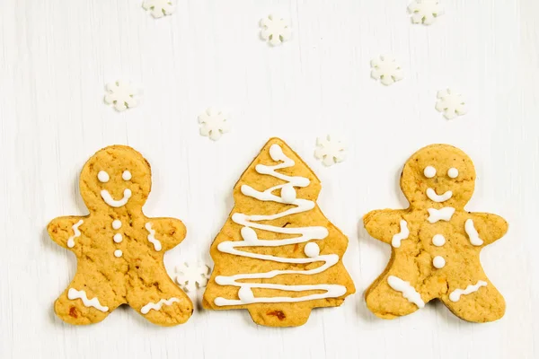 Gingerbread men friends at the Christmas tree on a white wooden — Stock Photo, Image