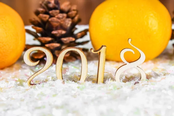 Cifras de madera de 2018 sobre nieve. Ambiente navideño. El nuevo año 2018. Mandarinas y conos . — Foto de Stock