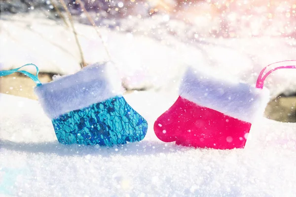 蓝色和粉红色的手套在雪地上拥抱。圣诞玩具男性和女性. — 图库照片