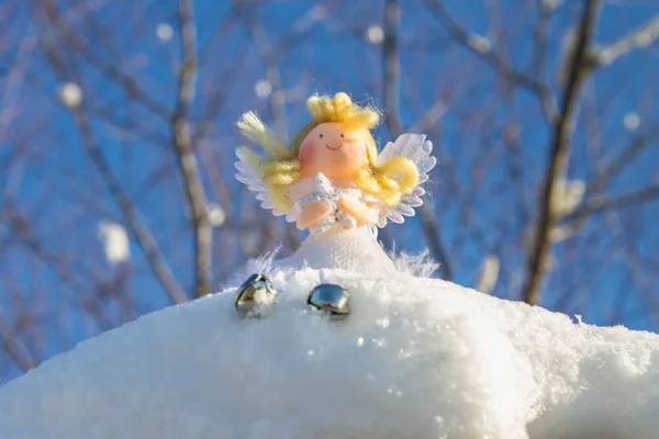 一个童话般的天使玩具坐在雪地上。圣诞玩具. — 图库照片