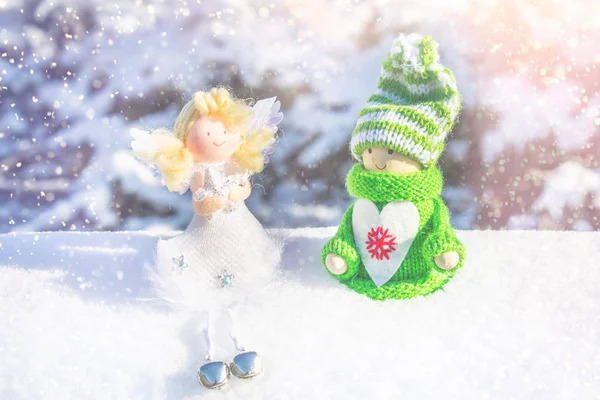 Игрушечная деревянная девочка в скандинавском стиле в трикотажной зеленой одежде на снегу и ангеле. Рождественские игрушки . — стоковое фото