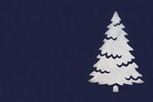 Ein weißer Weihnachtsbaum, der mit Farbe durch eine Schablone auf dunkelblauem Hintergrund gemalt wurde. Kopierraum. — Stockfoto