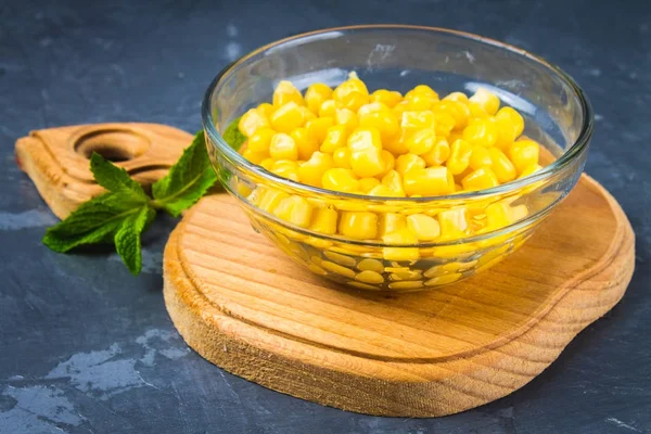 Canned corn in a glass plate on a gray concrete background. — Stock Photo, Image