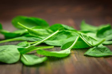 Taze sulu ıspanak ahşap bir kahverengi masa üzerinde bırakır. Doğal ürünler, Yeşiller, sağlıklı gıda, vitaminler.