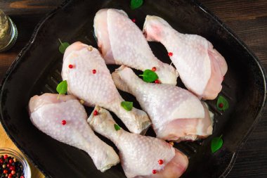 Ahşap bir masa üzerinde bir tavada çiğ tavuk budu. Et yemek pişirmek için malzemeler. Üstten Görünüm.