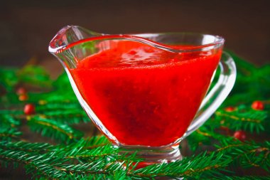 Fuska kızılcık sosuna çam dalları ile ahşap bir masa üzerinde bir cam temiz daire.