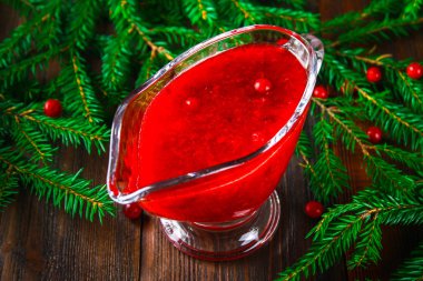 Fuska kızılcık sosuna çam dalları ile ahşap bir masa üzerinde bir cam temiz daire.