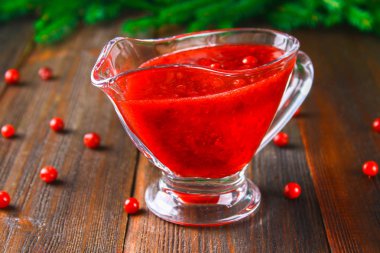 Fuska kızılcık sosuna çam dalları ile ahşap bir masa üzerinde bir cam temiz daire.