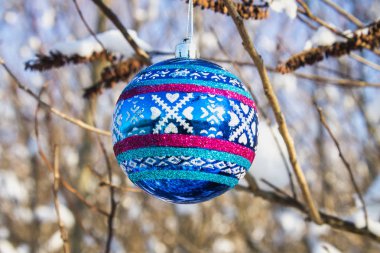 Bir dalı ile kar üzerinde mavi bir yeni yıl top asılı. Noel oyuncaklar.