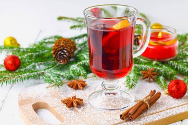 Dal, arka planda bir bardak içinde yeni yıl mulled şarap ve mumlar çelenk.