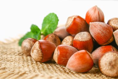 Beyaz ahşap bir masa üzerinde çul üzerinde dağınık ceviz fındık.