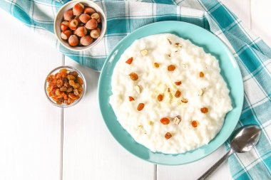 Pirinç sütü yulaf lapası ile fındık ve kuru üzüm bir WHI üzerinde mavi bir tabak içinde