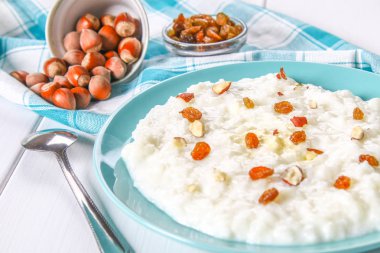 Pirinç sütü yulaf lapası ile fındık ve kuru üzüm bir WHI üzerinde mavi bir tabak içinde