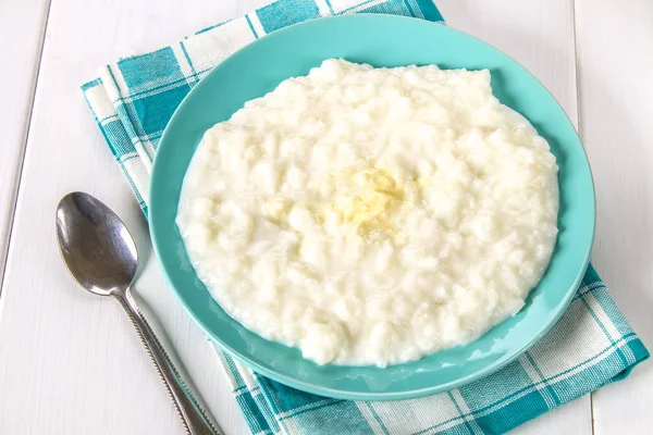 Pirinç sütü yulaf lapası ile fındık ve kuru üzüm bir WHI üzerinde mavi bir tabak içinde — Stok fotoğraf