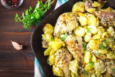 Kimyon ve sarımsak ile patates ile kavrulmuş tavuk budu.