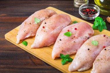 Çiğ tavuk fileto kesme tahtası ahşap bir masa arka planı. Yemek pişirmek için et malzemeler.