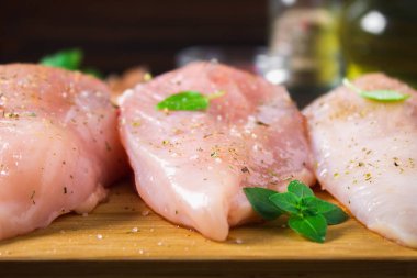 Çiğ tavuk fileto kesme tahtası ahşap bir masa arka planı. Yemek pişirmek için et malzemeler.