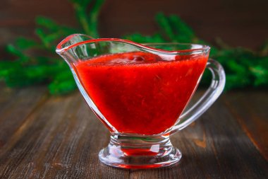 Fuska kızılcık sosuna çam dalları ile ahşap bir masa üzerinde bir cam temiz daire.