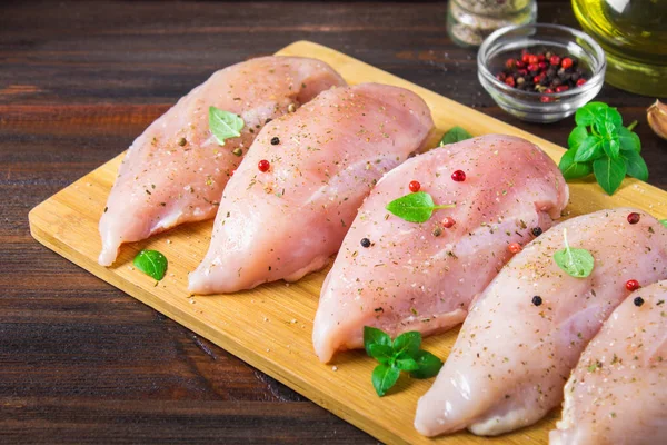 Çiğ tavuk fileto kesme tahtası ahşap bir masa arka planı. Yemek pişirmek için et malzemeler.