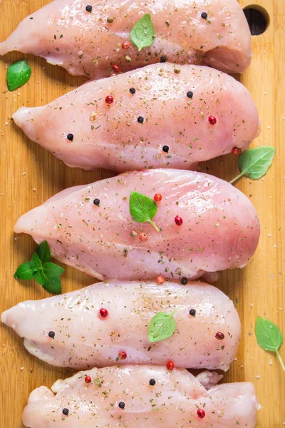 Çiğ tavuk fileto kesme tahtası ahşap bir masa arka planı. Et yemek pişirmek için malzemeler. Düz lei. Üstten Görünüm.