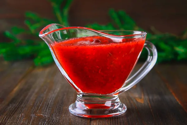 Fuska kızılcık sosuna çam dalları ile ahşap bir masa üzerinde bir cam temiz daire.