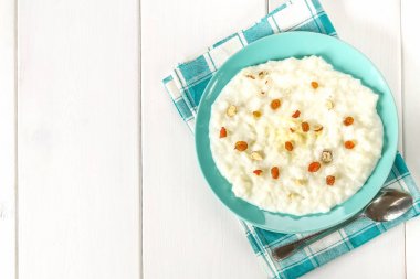 Pirinç sütü yulaf lapası ile fındık ve kuru üzüm bir WHI üzerinde mavi bir tabak içinde