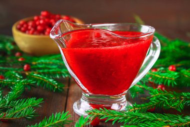 Fuska kızılcık sosuna çam dalları ile ahşap bir masa üzerinde bir cam temiz daire.