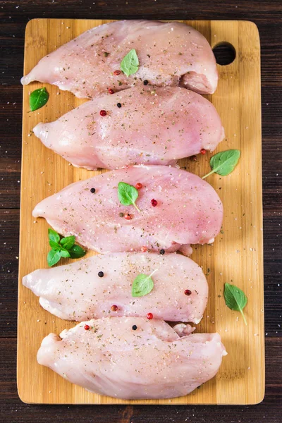 Çiğ tavuk fileto kesme tahtası ahşap bir masa arka planı. Et yemek pişirmek için malzemeler. Düz lei. Üstten Görünüm.