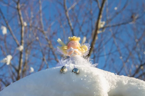 A fairy angel toy sits on the snow. Christmas toys. — Stock Photo, Image