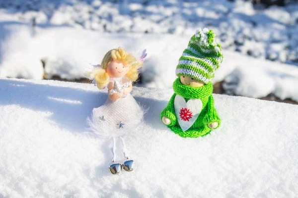 Игрушечная деревянная девочка в скандинавском стиле в трикотажной зеленой одежде на снегу и ангеле. Рождественские игрушки . — стоковое фото