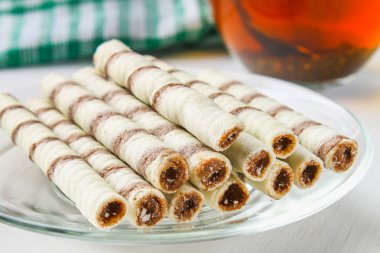 Çizgili gofret rulo, lezzetli çikolata meze Beyaz ahşap tablo.