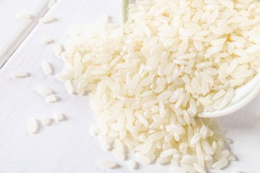 Kurulların Beyaz ahşap bir masa üzerinde çiğ beyaz pirinç taneleri. Yemek pişirmek için malzemeler.