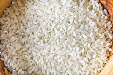 Kurulların Beyaz ahşap bir masa üzerinde çiğ beyaz pirinç taneleri. Yemek pişirmek için malzemeler.