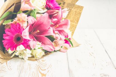 Bir buket çiçek bir zambak, gerbera, beyaz gül ve Beyaz ahşap bir masa üzerinde alstroemeria. Bir tatil, bir hediye.