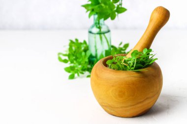 Hafif bir arka plan üzerinde ahşap bir harç yeşil limon fesleğen. Fesleğen şişe.