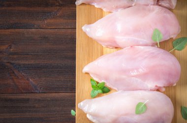 Çiğ tavuk fileto kesme tahtası ahşap bir masa arka planı. Et yemek pişirmek için malzemeler. Bir yazıt için boş yer. Uzay kopyalayın. Düz lei. Üstten Görünüm.