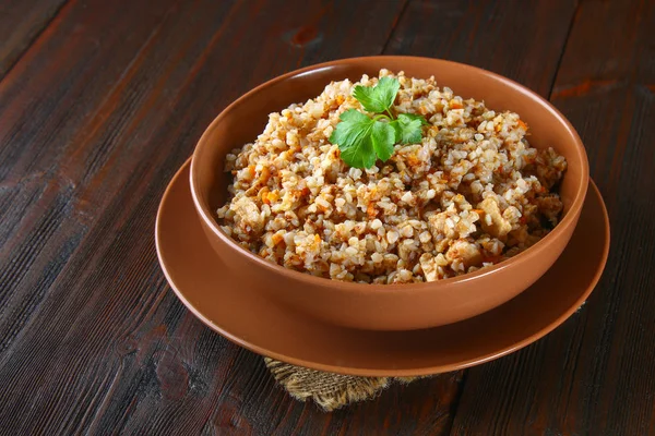 Sarrasin bouilli dans un bol avec morceaux de viande de poulet et coriandre sur une table en bois brun . — Photo