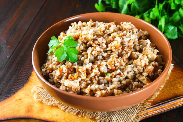 Sarrasin bouilli dans un bol avec morceaux de viande de poulet et coriandre sur une table en bois brun . — Photo