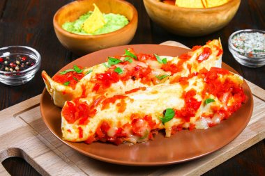 Homemade chicken enchiladas in dish on wooden table. Top view. clipart