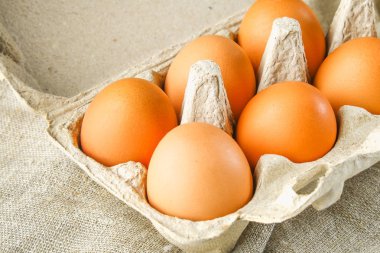 Sivas'tan bir beyaz tahta tabloda hücre ile bir karton tepsisinde ham kahverengi tavuk yumurtası. Yemek pişirmek için malzemeler.