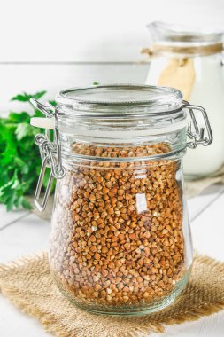 Ham buğday Sivas'tan maydanoz arka plan üzerinde ahşap bir masa üzerinde bir cam kavanoza. Sağlıklı bir diyet yemek.