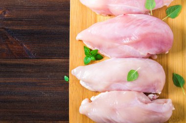 Çiğ tavuk fileto kesme tahtası ahşap bir masa arka planı. Et yemek pişirmek için malzemeler. Bir yazıt için boş yer. Uzay kopyalayın. Düz lei. Üstten Görünüm.