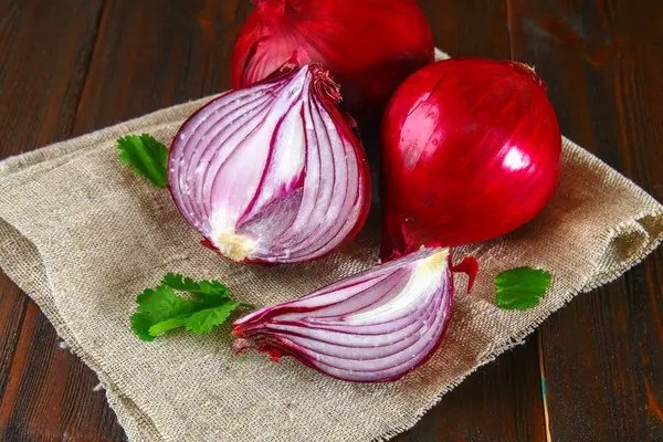 Fresh red onions and chopped slices on a wooden table. — Stock Photo, Image