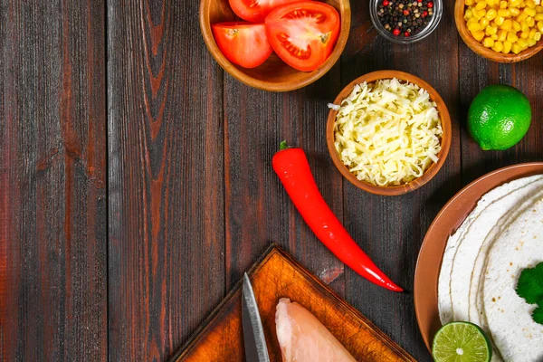 Składniki do gotowania tradycyjnych meksykańskich enchiladas. Pomidory, kolendry, czerwona cebula, filet z kurczaka, tortille, kukurznye placki, ser cheddar, chili. Widok z góry. — Zdjęcie stockowe