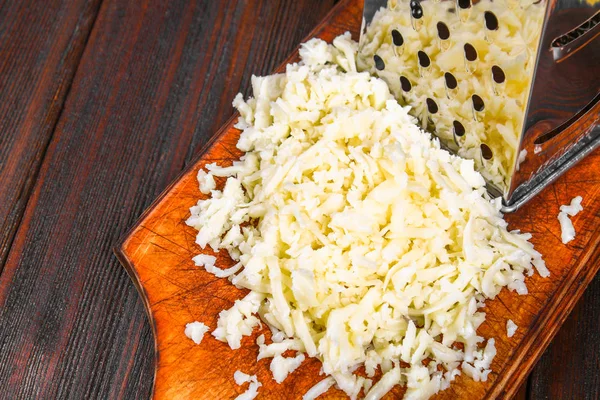 소박한 나무 테이블에 강판된에 체 다 치즈의 부분. — 스톡 사진