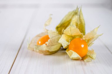 Egzotik meyveler physalis Beyaz ahşap bir masa üzerinde.