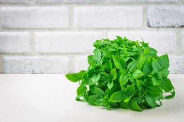 Bir tuğla duvar arka plan beyaz bir beton masada yeşil limon fesleğen demet