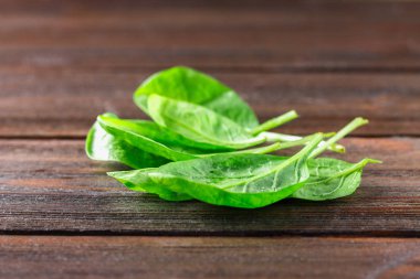 Ahşap bir masa üzerinde yeşil taze ıspanak yaprakları.