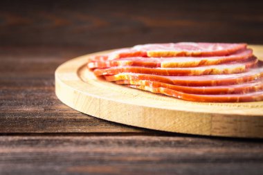 Taze yeşil salata ile dilimlenmiş jambon yuvarlak kesme tahtası üzerinde bırakır. Et ürünleri bir kahverengi ahşap tablo.